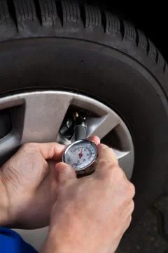 Cropped image of mechanic checking tire pressure using gauge 写真素材