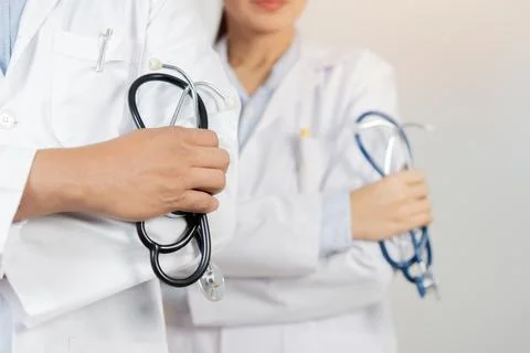 Cropped image of two determined physicians wearing white medical gowns stan.. Stock Photos