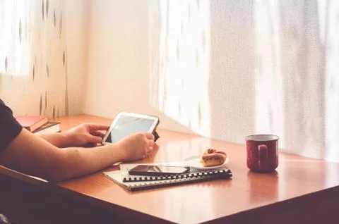 Cropped man working from from home. Using computer and eating donuts. Foto stock