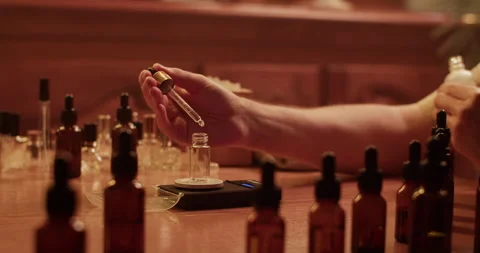 Cropped perfumer measuring weight of oil drop Stock Footage 260984612