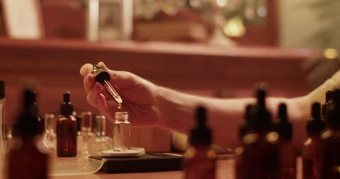 Cropped perfumer mixing oils while creating perfume Stock Footage 260987126