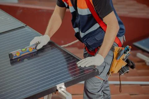 Cropped Professional worker installing solar panels on a house roof Stock Photos
