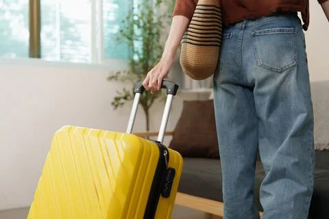 Cropped rear view of person pulling yellow luggage suitcase for travel trip Stock Photos