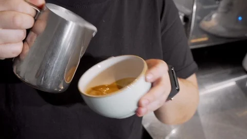 Cropped shot of a barista adding hot milk into coffee in a cup 動画素材 116890503