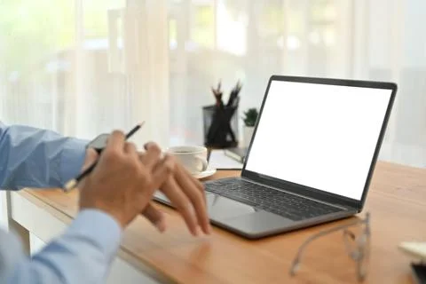 Cropped shot of businessman using checking time on his watch and using laptop on Stock Photos