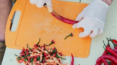 Cropped shot of a man cutting red hot peppers, wearing white latex gloves. Cl Stock Footage 286368917