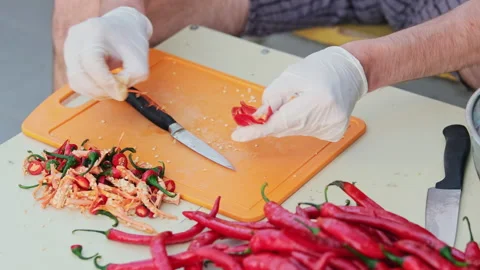 Cropped shot of a man cutting red hot peppers, wearing white latex gloves. Cl Vídeo Stock 286368967