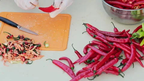 Cropped shot of a man cutting red hot peppers, wearing white latex gloves. Cl Stock Footage 286376891