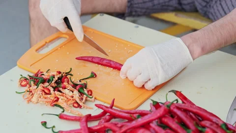 Cropped shot of a man deseeding red hot peppers, wearing white latex gloves.  Stock-Footage 286368045