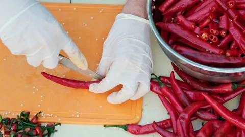 Cropped shot of a man deseeding red hot peppers, wearing white latex gloves.  Stock-Footage 286370747