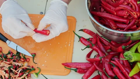 Cropped shot of a man deseeding red hot peppers, wearing white latex gloves.  Stock Footage 286375743