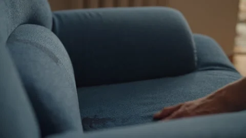 Cropped shot of man inspecting red wine stain on couch and pouring wine out of Stock Footage 313716748