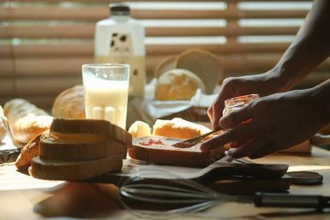 Cropped shot of man preparing breakfast, spreading tasty  strawberry jam on.. Stock Photos