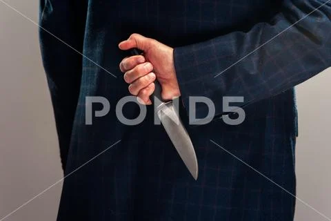 Cropped shot of senior businessman in suit with knife behind back Stock Photos