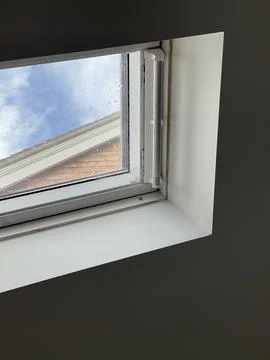 Cropped shot of a small window in the ceiling, blue sky seen through Stock Photos