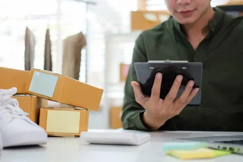 Cropped shot young man using digital tablet and preparing parcels for shipmen Stock Photos