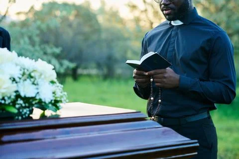 Cropped shot of young priest in black clothes reading verses from Holy Bible Stock Photos