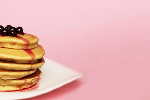Cropped stack of pancakes with blackcurrant at the top, pink background. Stock Photos