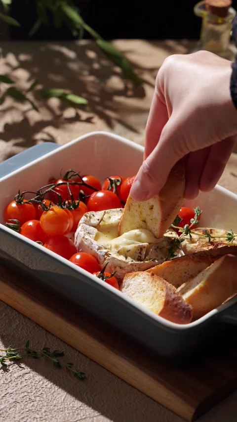 Cropped unrecognizable person's hand dipping bread into gooey Camembert cheese Stock Footage 330616410