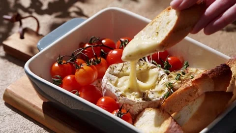 Cropped unrecognizable person's hand dipping bread into gooey Camembert cheese Stock Footage 330616418