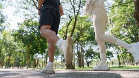 Cropped view of active couple jogging together in park for outdoor workout Stock Photos
