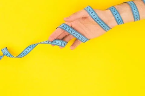 Cropped view of man holding measuring tape isolated on yellow Foto stock