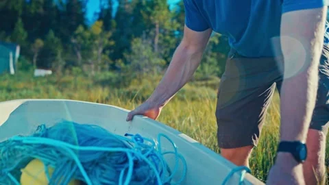 Cropped View Of A Man Placing His Fishing Boat On A Grassy Lakeshore. Close-up Stock-Footage 336902245