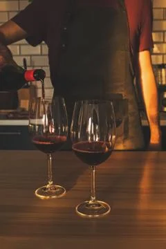 Cropped view of man pouring red wine in the glasse at his kitchen Stock Photos