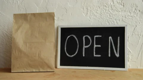 Cropped view of man putting disposable cups near paper bag and open signboard Stock-Footage 133783946