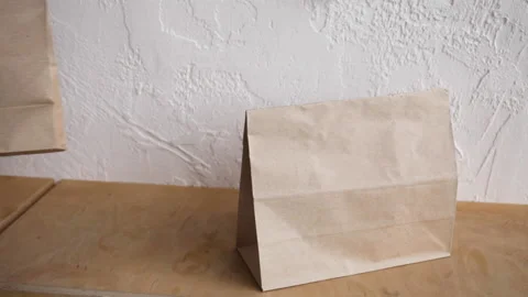 Cropped view of man in putting paper bag and disposable cup on wooden surface Stock-Footage 132445940