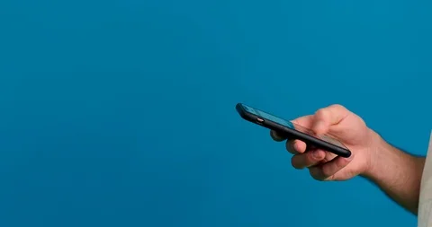 Cropped view of man scrolling feed on smartphone isolated on blue background 스톡 동영상 124905159