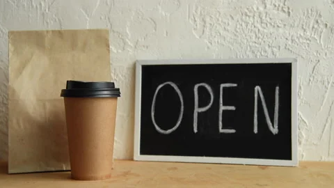 Cropped view of man taking disposable cup and paper bag near open signboard Stock-Footage 133782161