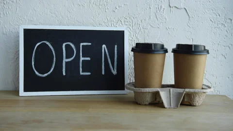 Cropped view of man taking open signboard near disposable cups 库存影片 133780156
