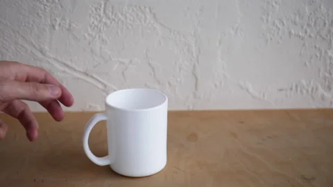 Cropped view of man taking white mug from wooden surface 库存影片 132444590