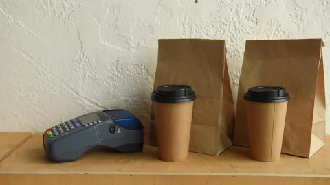 Cropped view of man using payment terminal near paper bags and disposable cups Stock-Footage 133782282