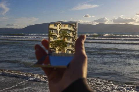Cropped view of mirror with reflection of palm tree and building Stock Photos