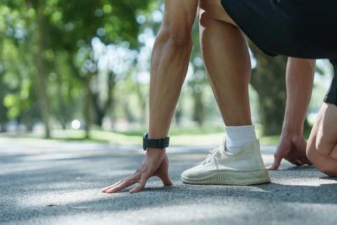 Cropped view of runner in starting position on park track for athletic training Stock Photos