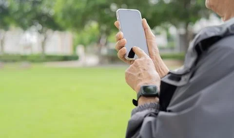 Cropped view of senior man using mobile phone in a field at sunset. Senior .. Stock Photos