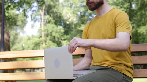 Cropped view of smiling man using laptop in park 库存影片 136115713
