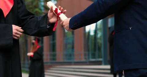 Cropped view of the two graduated students shaking hands to each other while Stock Photos