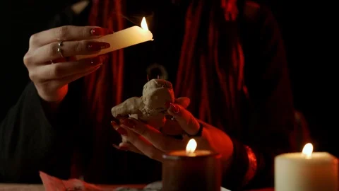 Cropped view of witch with candle dripping wax on voodoo doll during occult Stock Footage 125838859