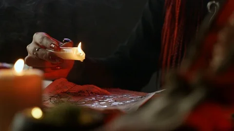 Cropped view of witch holding candle during ceromancy ritual with ancient Stock Footage 123958339