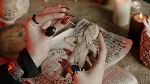 Cropped view of witch with rings sticking needle in voodoo doll 스톡 동영상 125024196