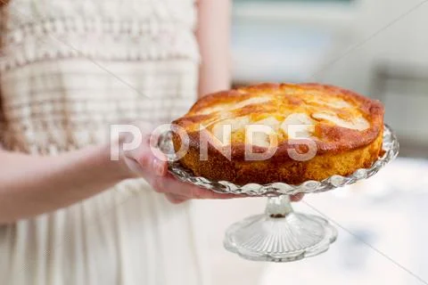 Cropped View Of Woman Holding Cake On Glass Cakestand