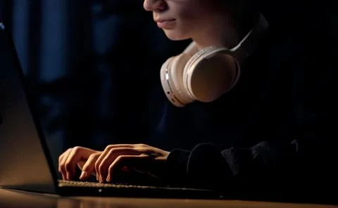 Cropped view of young computer gamer in glasses with headphones on neck typ.. Stock Photos