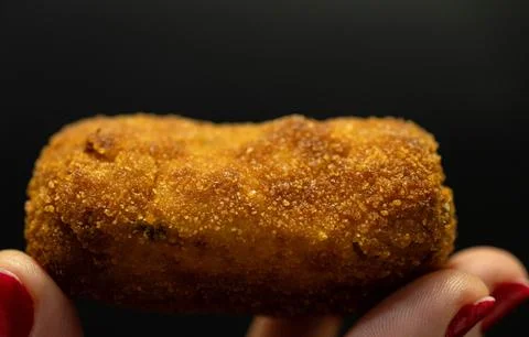 A croquette held by one hand Stock Photos