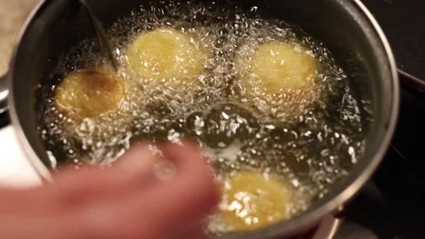 Croquettes frying in a pan while a chef stirs them with a fork Stock Footage 320351523