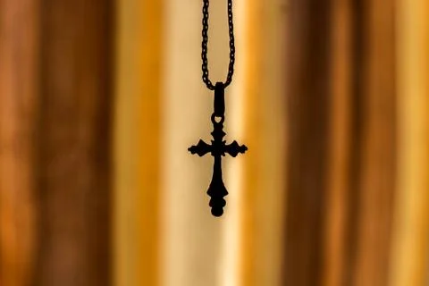 A cross on a chain on an orange background Stock Photos