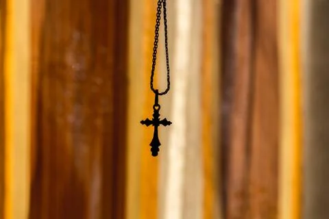 A cross on a chain on an orange background Stock Photos