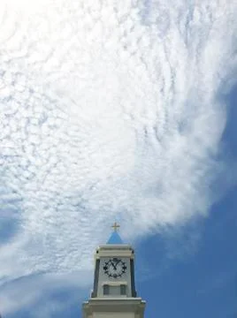 Cross on Clock tower with Cirrocumulus cloud and sky background Stock Photos